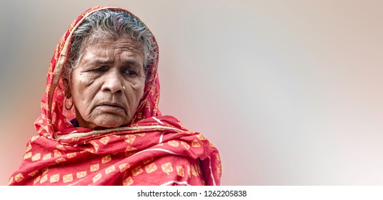 Beautiful portrait of an Indian Origin elderly woman, having wrinkles on her face and white & grey hair, wearing red saree with veil, thinking in sorrow. Plane background space for tagline/advertising - Shutterstock ID 1262205838