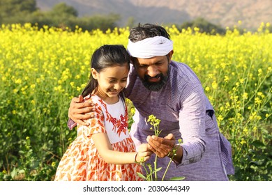 Beautiful portrait of Indian rural happy farmers. Father and daughter standing in a mustard field enjoying the flourished agriculture crops in a day time in summer