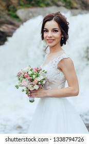 Beautiful portrait of a luxurious bride in nature on the background of a waterfall.