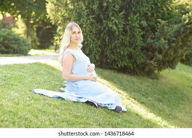 Beautiful portrait of a pregnant woman on a warm summer day in the nature. Pregnancy and season concept