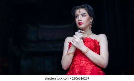 Beautiful Portrait Pretty Woman Red Dressed As An Indian Sexy Girl With Red Lips. Young Hindu Pakistani Bride And Glamour Makeup In A Fashion Jewelry Set. Traditional Indian Red Sari Clothing.