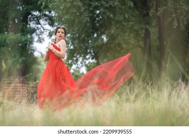 Beautiful Portrait Pretty Woman Red Dressed As An Indian Sexy Girl With Red Lips. Young Hindu Pakistani Bride And Glamour Makeup In A Fashion Jewelry Set. Traditional Indian Red Sari Clothing.