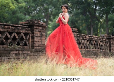 Beautiful Portrait Pretty Woman Red Dressed As An Indian Sexy Girl With Red Lips. Young Hindu Pakistani Bride And Glamour Makeup In A Fashion Jewelry Set. Traditional Indian Red Sari Clothing.