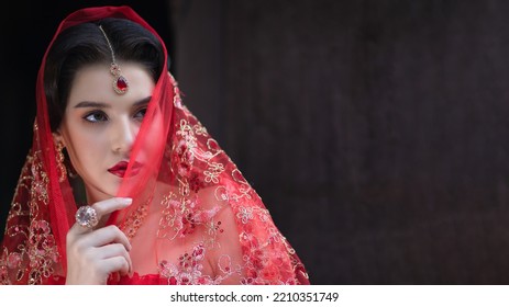 Beautiful Portrait Pretty Woman Red Dressed As An Indian Sexy Girl With Red Lips. Young Hindu Pakistani Bride And Glamour Makeup In A Fashion Jewelry Set. Traditional Indian Red Sari Clothing.