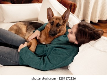 Beautiful portrait of smiling woman hugging her dog german shepherd together in front of fireplace at cozy home in winter day in happiness Friendship Love Companionship and benefits of pets animals. - Powered by Shutterstock