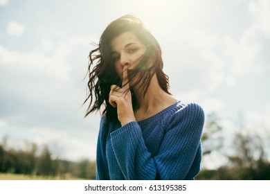 Beautiful portrait of young brunette woman show quiet sign with the wind blowing hair on nature background. Pretty female silent quiet gesture with finger. Secret. Lifestyle concept.