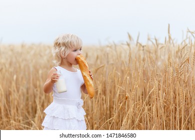  Beautiful Portrait Of A Young Child In A Field. Children With Bread. Little Girl In Cereal Field.  Happy Baby Girl On Field Of Wheat With Bread. Food And Drink. Little Girl Drinking Milk. 