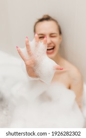 Beautiful Portrait Of Young Happy Smiling Woman Takes A Bath All In Foam. Spa Relaxation Fun And Self Care	