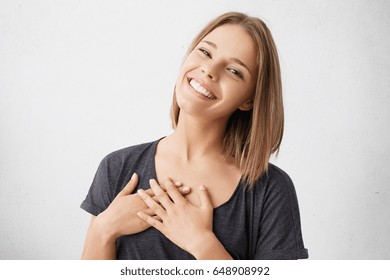 Beautiful positive friendly-looking young mixed race woman with lovely sincere smile feeling thankful and grateful, showing her heart filled with love and gratitude holding hands on her breast - Shutterstock ID 648908992