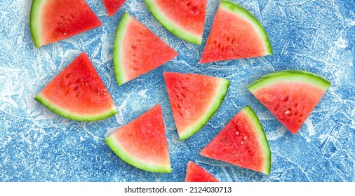 Beautiful Poster With Sliced Red Watermelon Closeup. Group Triangle Pieces Of Watermelon On Ice Blue Background. Bright Food Wallpaper Of Fresh Watermelon. Top View. Flat Lay.