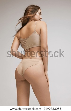 Beautiful posture and buttocks without cellulite. Back view of young woman in underwear isolated on gray background. Wellness, weight loss, treatment, health care, fitness