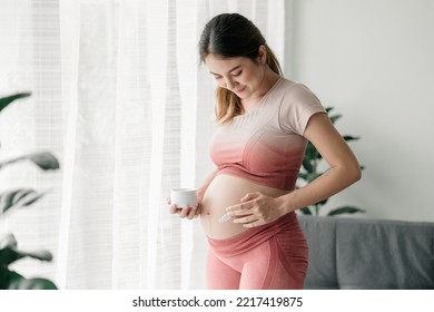 Beautiful pregnant asian woman is in exercise outfits, applying pregnancy stretch mark protection cream on her belly, pregnancy product, pregnacy care, prenatal preparation. - Powered by Shutterstock