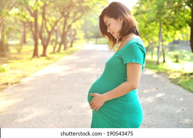 Beautiful pregnant Asian woman feeling lovely and Relax in the park with warm light in morning - Powered by Shutterstock