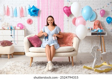 Beautiful pregnant happy woman with baby booties sitting at home. Gender reveal party concept - Powered by Shutterstock