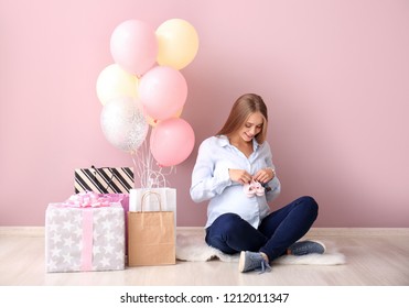 Beautiful Pregnant Woman With Baby Shower Gifts Near Color Wall