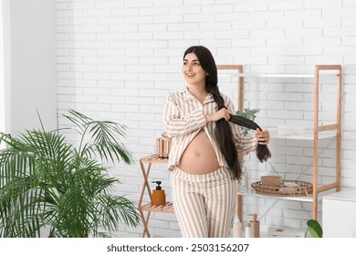 Beautiful pregnant woman braiding long hair at home - Powered by Shutterstock