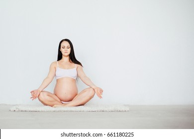 Beautiful pregnant woman doing prenatal yoga exercises - lotos pose, healthy  lifestyle concept
