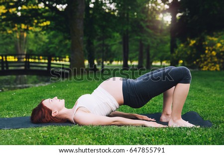 Beautiful pregnant woman doing prenatal yoga on nature outdoors. 