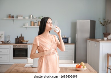 Beautiful Pregnant Woman Drinking Milk In Kitchen