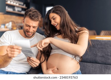 beautiful pregnant woman with exposed belly showing ultra sound to her partner, concept happy expecting parents - Powered by Shutterstock