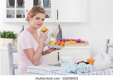 Schöne schwangere Frau mit frischem Obst in der Hausküche.