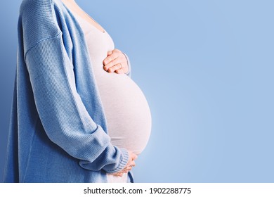 Beautiful pregnant woman hugging her belly in white background. Expectant mother waiting for baby birth during pregnancy. Concept of maternal health, visiting doctor and gynecological checkup.