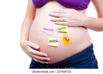 Beautiful pregnant woman, a model, holding her belly which has post it with words in portuguese. - Shutterstock ID 127444715