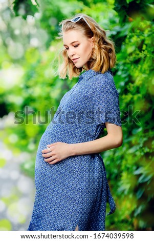 Beautiful pregnant woman outdoor in park. Pregnancy and motherhood. Fashion for pregnant women.