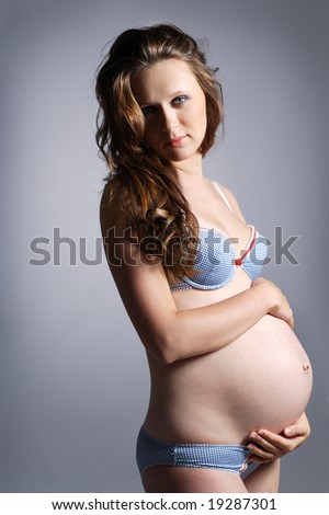 beautiful pregnant woman posing on grey
