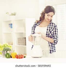Beautiful pregnant woman preparing breakfast in kitchen. Motherhood, pregnancy, maternity concept.