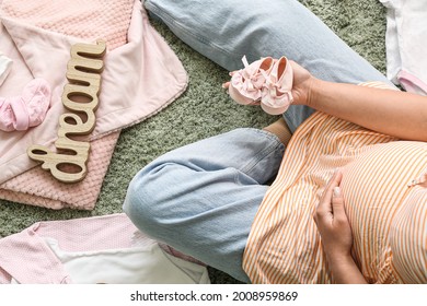 Beautiful Pregnant Woman Sitting On Floor With Baby Clothes, Top View