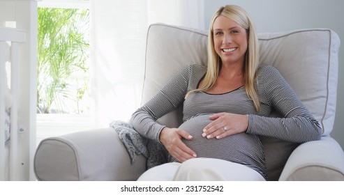 Beautiful pregnant woman sitting on rocking chair in nursery - Powered by Shutterstock