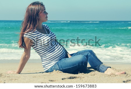 beautiful pregnant woman sitting on the beach