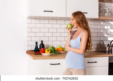 Beautiful pregnant woman smiling eat green apple in the kitchen Healthy food concept - Powered by Shutterstock