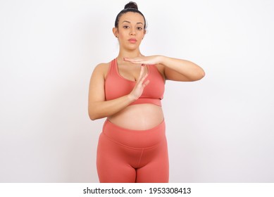 Beautiful pregnant woman in sports clothes against white background being upset showing a timeout gesture, needs stop, asks time for rest after hard work, demonstrates break hand sign - Powered by Shutterstock