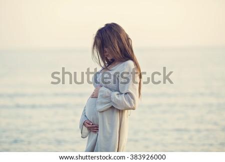 beautiful pregnant woman standing on the beach