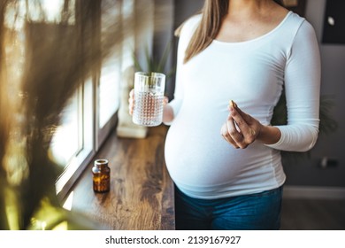 Beautiful Pregnant Woman Taking Pills For Morning Nausea. Close-up Of Pregnant Woman Hand With Glass Of Water And Vitamin Pill. Pregnant Woman On Medication