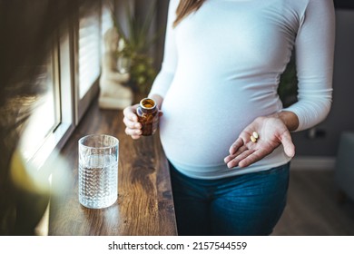 Beautiful Pregnant Woman Taking Pills For Morning Nausea. Close-up Of Pregnant Woman Hand With Glass Of Water And Vitamin Pill. Pregnant Woman On Medication