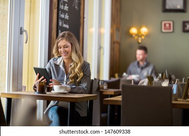 Beautiful pregnant woman using digital tablet at table in cafe - Powered by Shutterstock