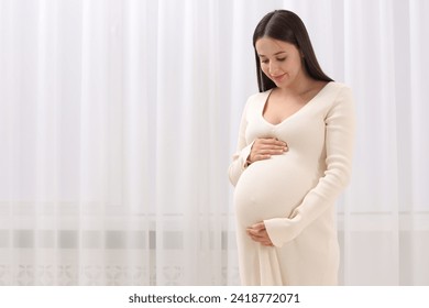 Beautiful pregnant woman in white dress indoors, space for text - Powered by Shutterstock