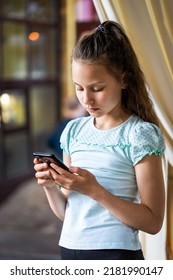 Beautiful Preteen Girl With Mobile Phone Standing In Restaurant Outdoor Area In Summer