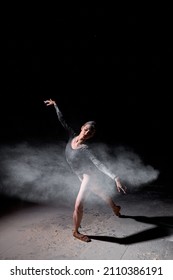 Beautiful Pretty Female Wearing Black Gymnastic Bodysuit Dancing With Flying Powder Flour, Full-length Portrait Of Attractive Caucasian Lady In Slow Motion. People, Dance, Art Concept