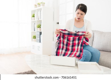 Beautiful Pretty Woman Received Online Shopping Package And Holding Clothing Finding Order Goods Is Wrong Feeling Shocked.