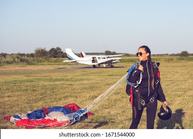 Beautiful pretty woman skydiver holding a parachute canopy after landing.