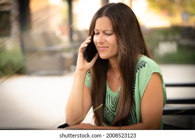 Beautiful Pretty Young Brunette Woman Break Up Angry Bullying Bad News Upset Talking On Smartphone Phone Cell Phone Hand To Ear Outside On At Mall Café With Natural Soft Daylight