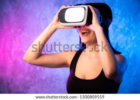 Beautiful Pro Gamer Girl Wearing Virtual Reality Headset Plays in Online Video Game, Gesturing. Cool Retro Neon Colors in the Room