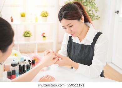 Beautiful Professional Asian Chinese Women Manicurist Checking Nail Care Of Her Client Ready To Doing The Beauty Salon Spa.