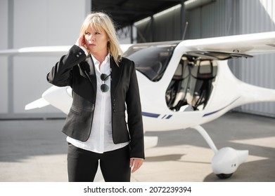 Beautiful Professional Female Spy Agent Bodyguard Securing Airplane On Private Airport. Security Police Woman In Civilian Black Suit. Close Security Protection