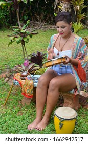 Beautiful Puerto Rican Woman Playing An Instrument And Singing Outside. Puerto Rico Music Culture. Lovely Woman Enjoying Music. Hispanic Hipster Female, Witchy Vibes. Natural Lighting Portrait.