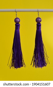 Beautiful purple earrings on a yellow background. Image with selective focus and noise effect.
